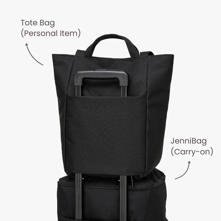 Black tote bag and carry-on bag stacked on a white background.